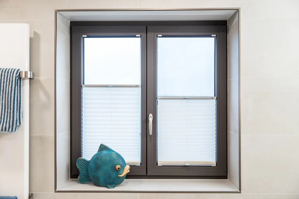 Passgenau eingebautes dunkles Fenster in einem hellen Bad